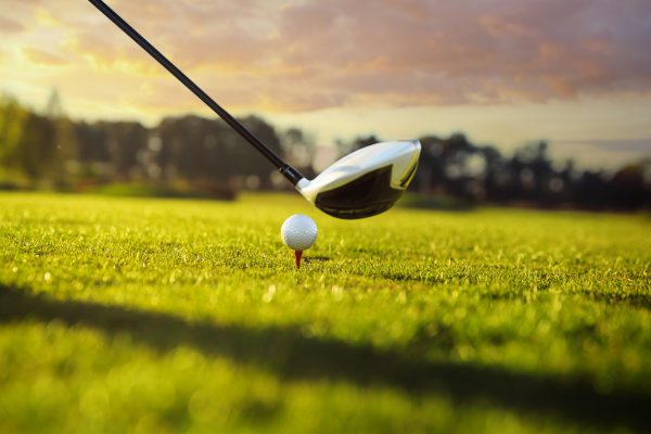 Golf ball on tee in front of driver