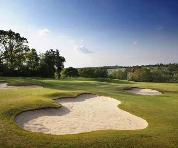 well trimmed grass with bunkers with blue skies at a golf course in harpenden